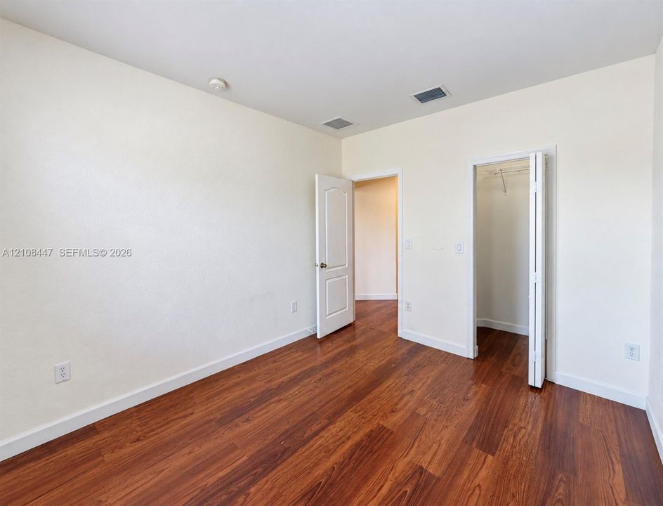 Room featuring wood-finish flooring, neutral wall paint, a six-panel interior door, and a built-in closet with bifold doors