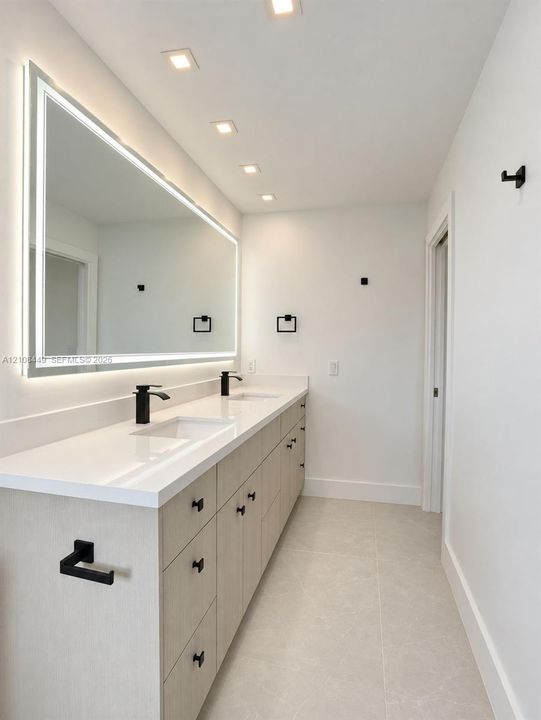 Dual-sink vanity with light-tone wood-finish cabinetry, solid surface countertop, matte black fixtures, and integrated LED-backlit mirror, finished with recessed ceiling lighting and tile flooring