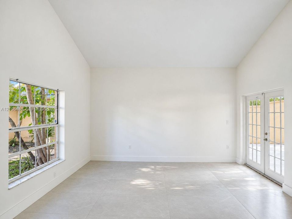 Vaulted ceilings, large-format tile flooring, oversized windows with grid patterns, and double glass-paned doors