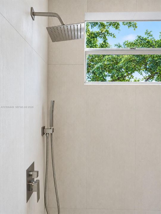 Shower stall featuring ribbed tile wall finishes, square rainfall showerhead, handheld shower wand, single-handle pressure balance valve, and window