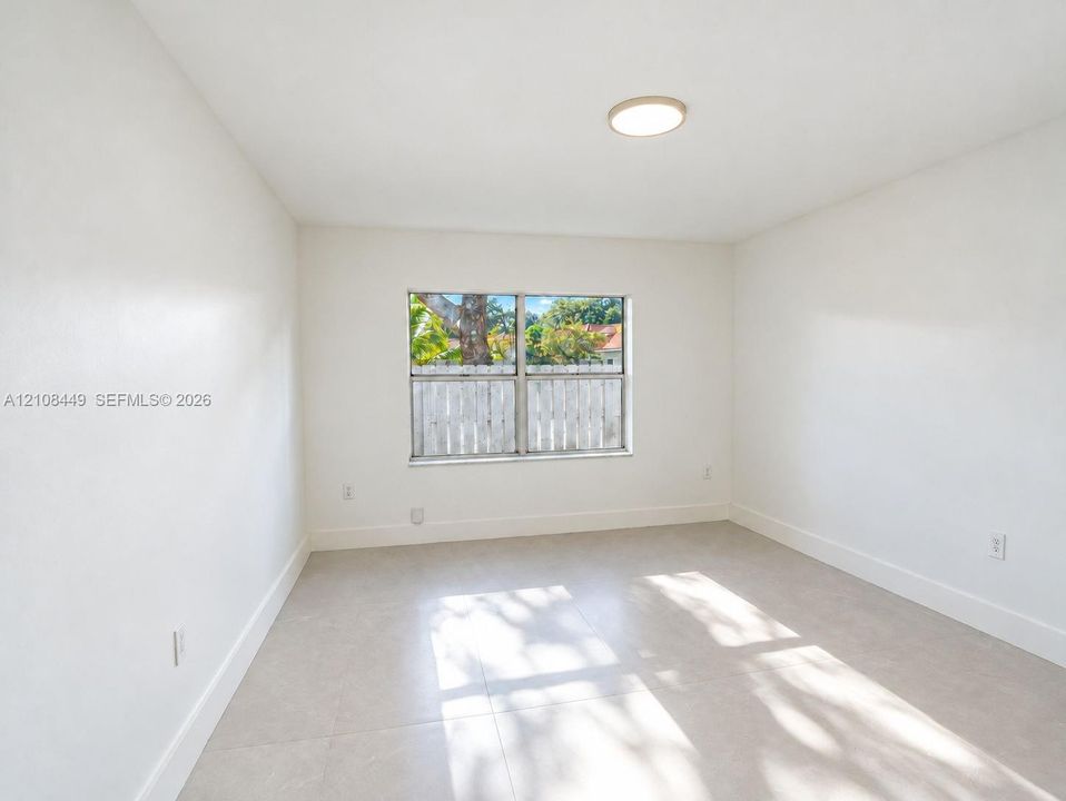 Neutral interior space featuring large-format ceramic tile flooring, solid-tone walls, and a recessed ceiling light fixture