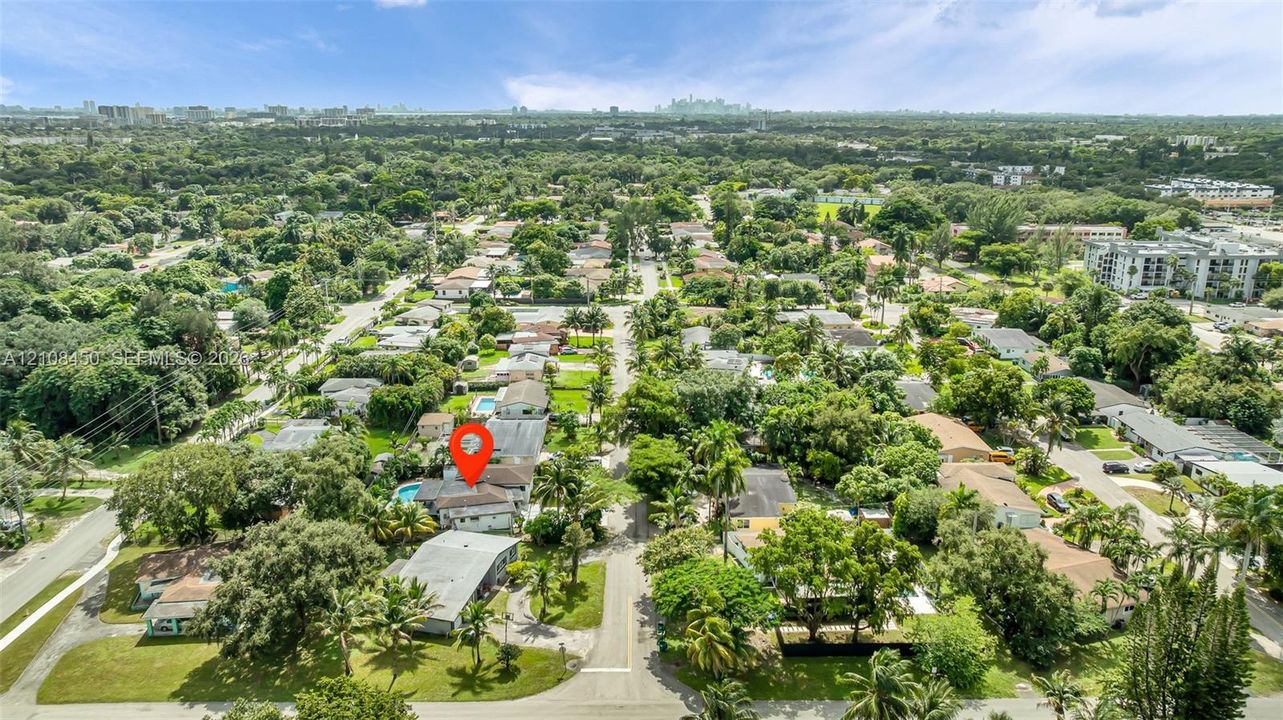 Aerial perspective featuring mature tree-lined streets, established residential landscaping, and a rear swimming pool