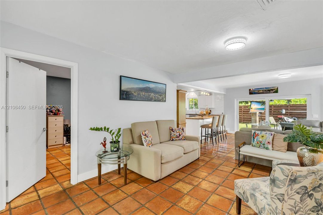 Terra cotta tile flooring, flush-mount lighting, sliding glass door, and a kitchen island with built-in cabinetry