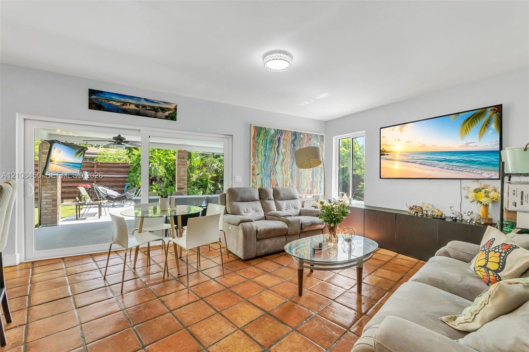 Living area featuring terracotta tile flooring, large sliding glass doors, built-in lower cabinetry, and recessed lighting
