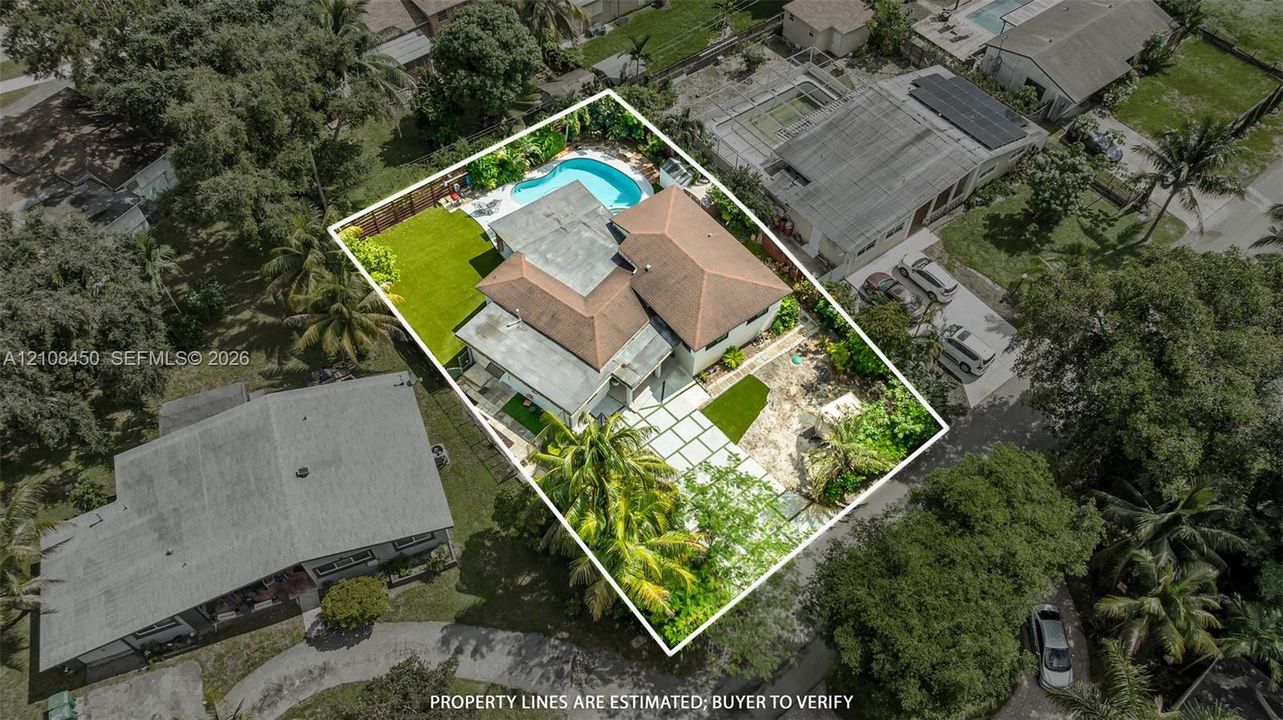 Aerial perspective featuring a multi-hipped roofline, in-ground swimming pool, fenced perimeter, and geometric paver driveway