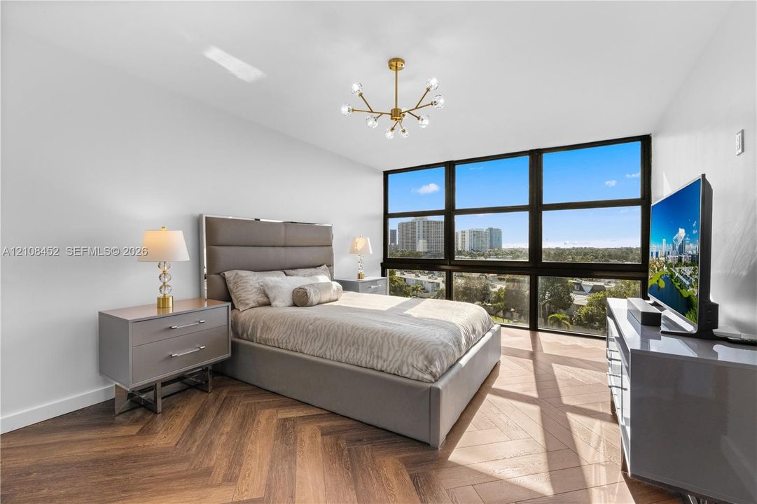 Herringbone-pattern wood-finish flooring, floor-to-ceiling windows with panoramic exterior surroundings, and a contemporary multi-arm sputnik chandelier