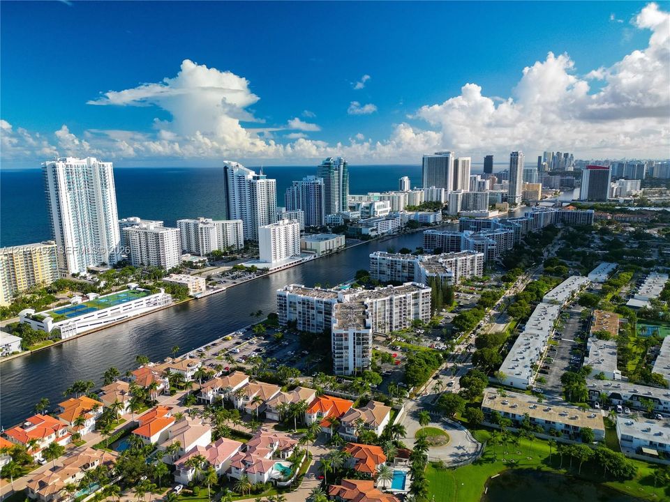 Aerial perspective showcasing a coastal residential community featuring waterfront access, high-rise buildings, and proximity to the ocean shoreline