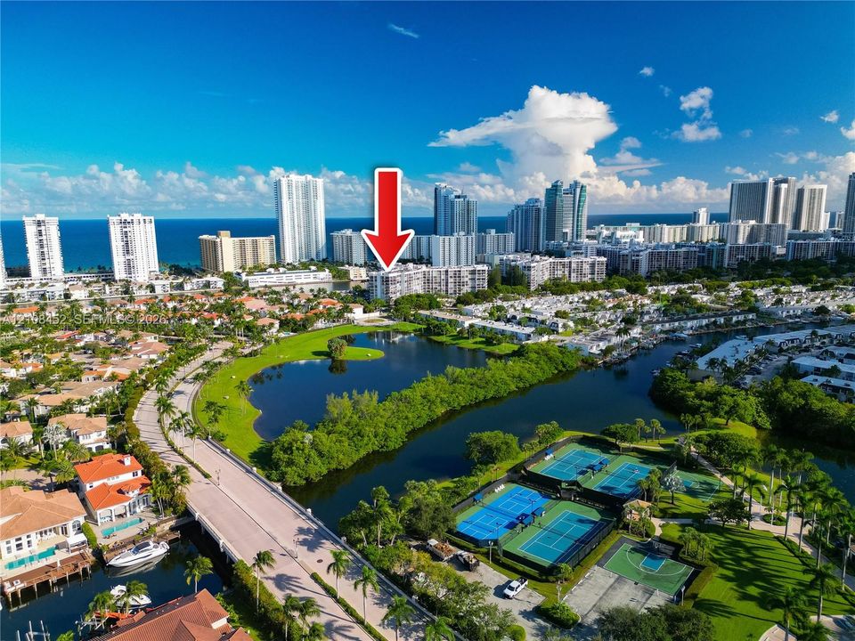 Aerial perspective of residential building with proximity to water features, tennis courts, and basketball court