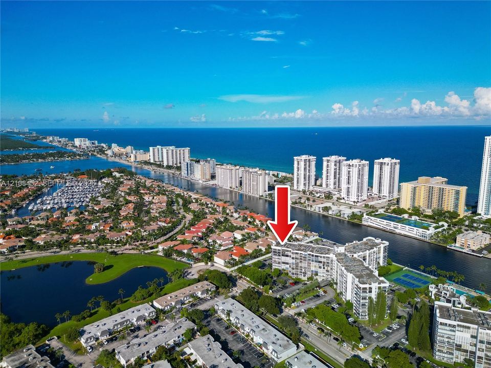 Aerial perspective of a multi-story residential building featuring proximity to coastal waterways and access to tennis courts