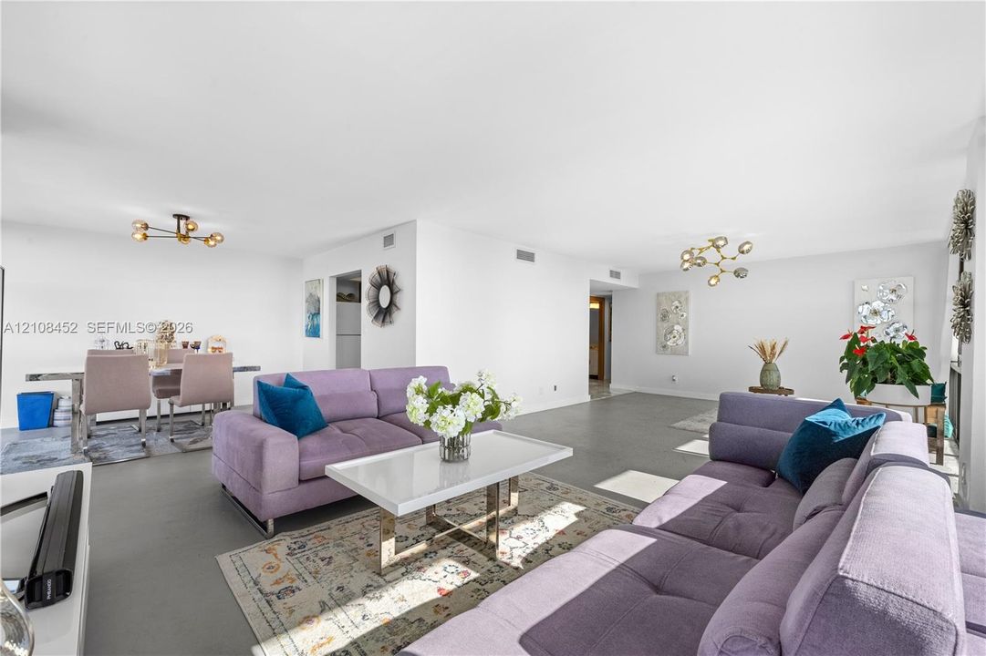 Open-concept interior featuring smooth flooring and two multi-arm modern light fixtures