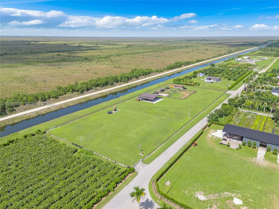 Expansive lot featuring perimeter fencing, canal frontage, cleared acreage, and paved road access