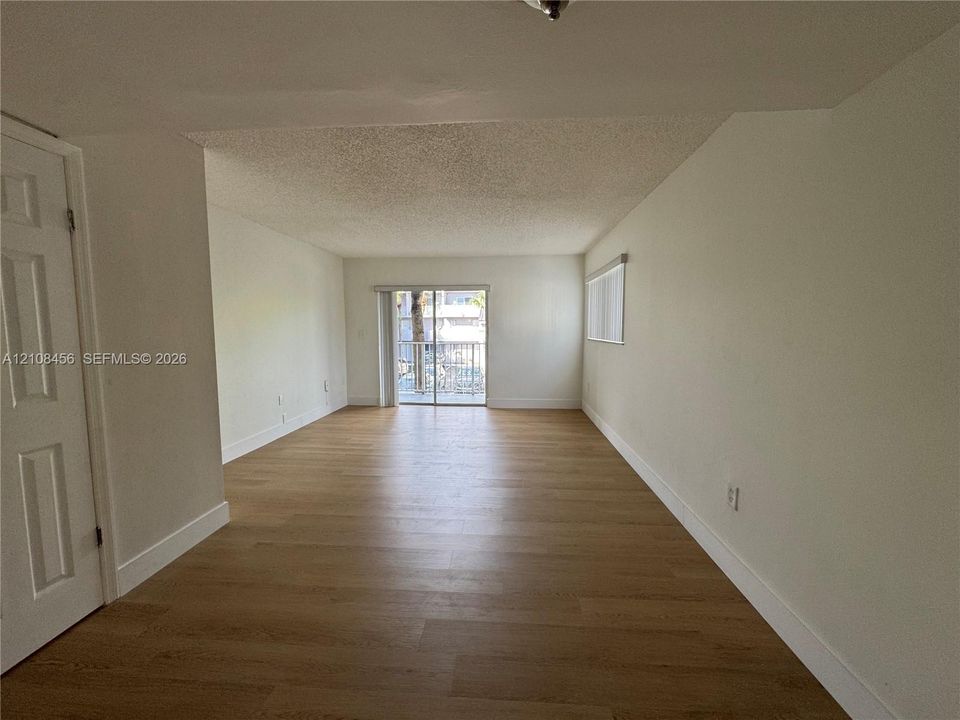 Interior space featuring wood-finish flooring, white walls, a multi-panel interior door, and a sliding glass door providing external access