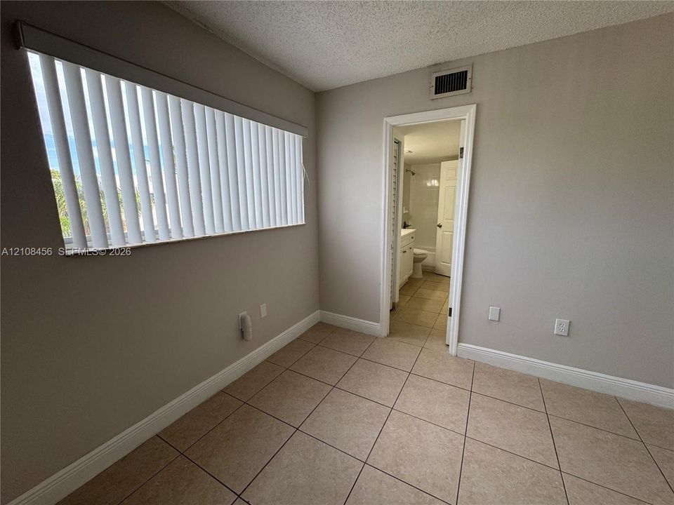 Neutral-toned walls paired with large-format tile flooring and horizontal window blinds