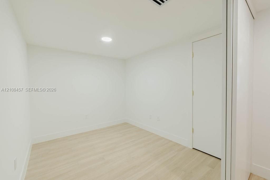 Interior space featuring light-toned wood-finish flooring, crisp white walls, recessed ceiling lighting, and a closet with sliding doors