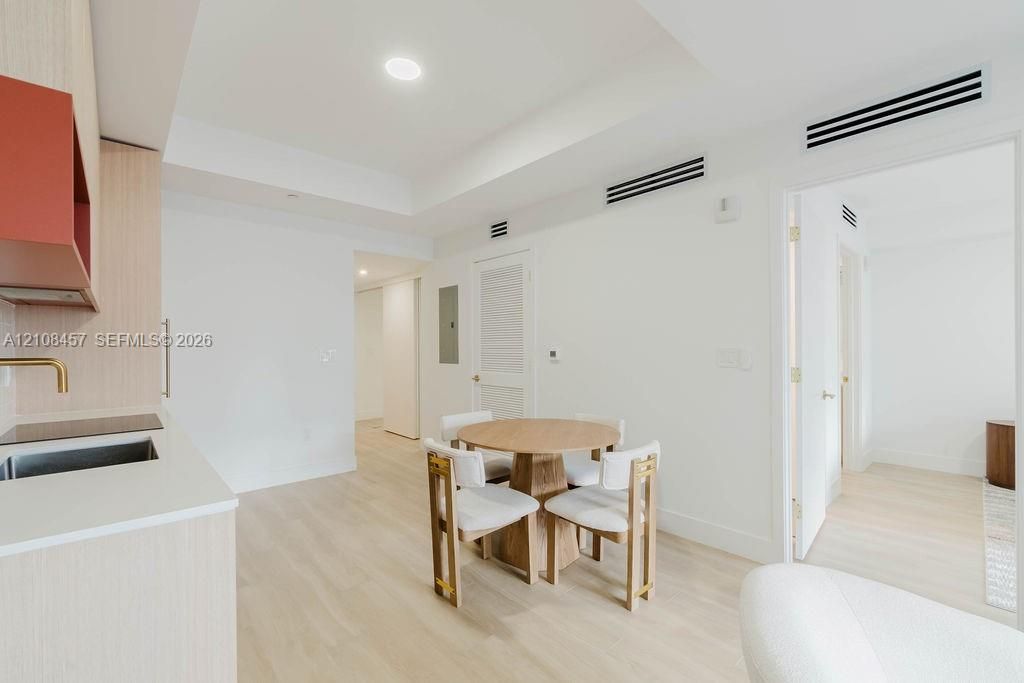 Light wood-finish flooring, recessed lighting, matte-finish solid surface countertops, metallic-finish faucet, and clean-lined cabinetry