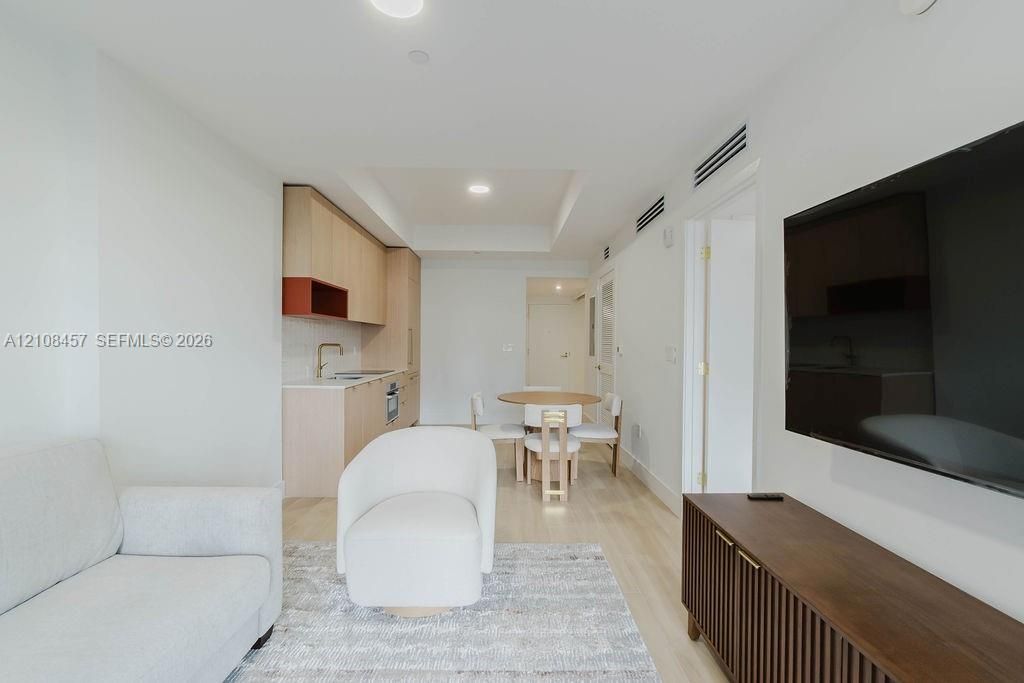 Light-toned wood-finish flooring, recessed lighting, and kitchen featuring flat-panel cabinetry with contrasting shelving