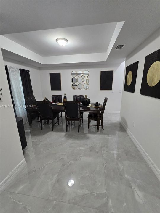 Tray ceiling featuring a central flush-mount light fixture and large-format tile flooring with a polished finish