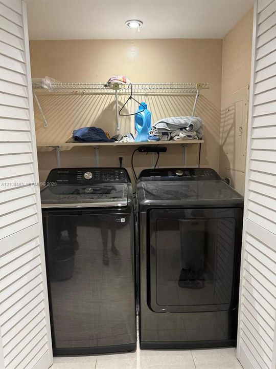 Laundry closet featuring louvered bi-fold doors, recessed ceiling lighting, and built-in upper shelving
