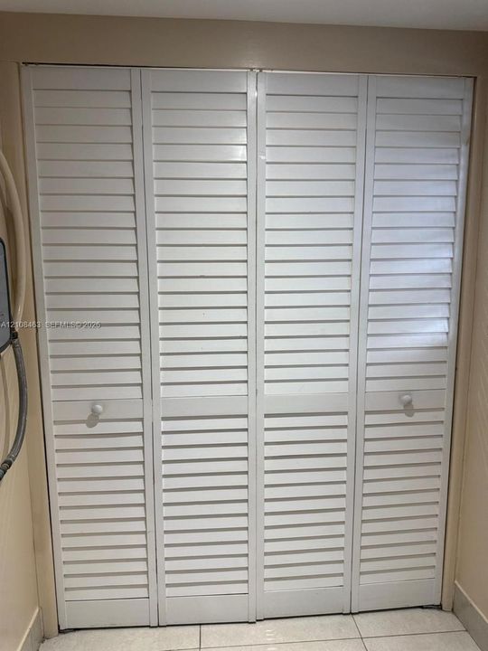 Bi-fold closet doors featuring white louvered panels and round hardware pulls