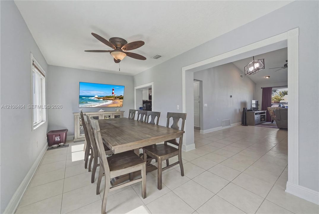 Neutral-toned tile flooring, multi-blade ceiling fan with integrated light fixture, and crown molding