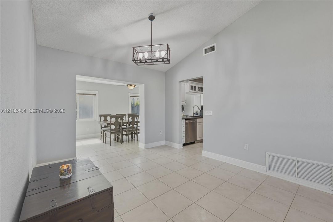 Vaulted ceilings, neutral wall tones, large-format tile flooring, and a linear metal-frame pendant light fixture