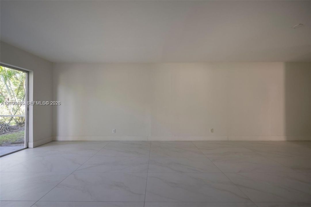 Large-format tile flooring, neutral wall tones, and glass sliding door providing outdoor access