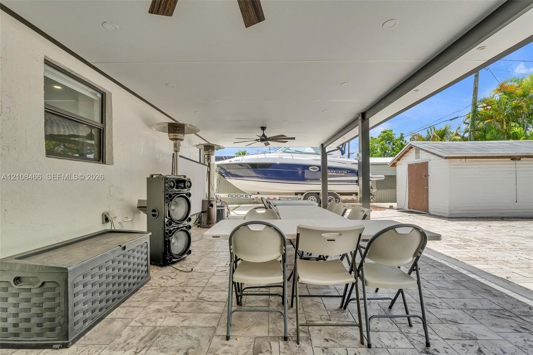 Covered patio featuring stamped concrete flooring, a ceiling fan, and recessed lighting, with an exterior storage structure