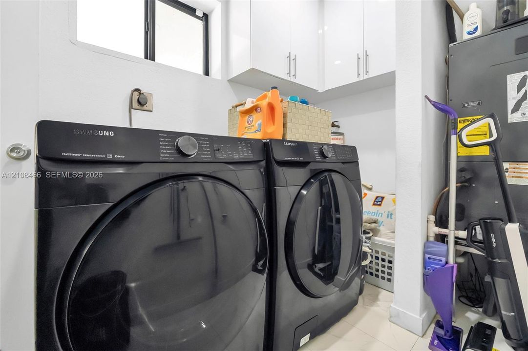 Dedicated utility area featuring white shaker-style cabinetry with brushed nickel hardware and a window for natural light