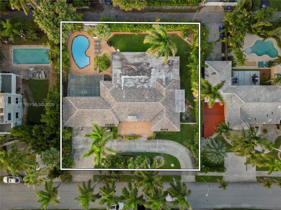 Aerial perspective featuring a tile-roof residence with a curved driveway, a screened-in patio, and an outdoor swimming pool set within a landscaped lot
