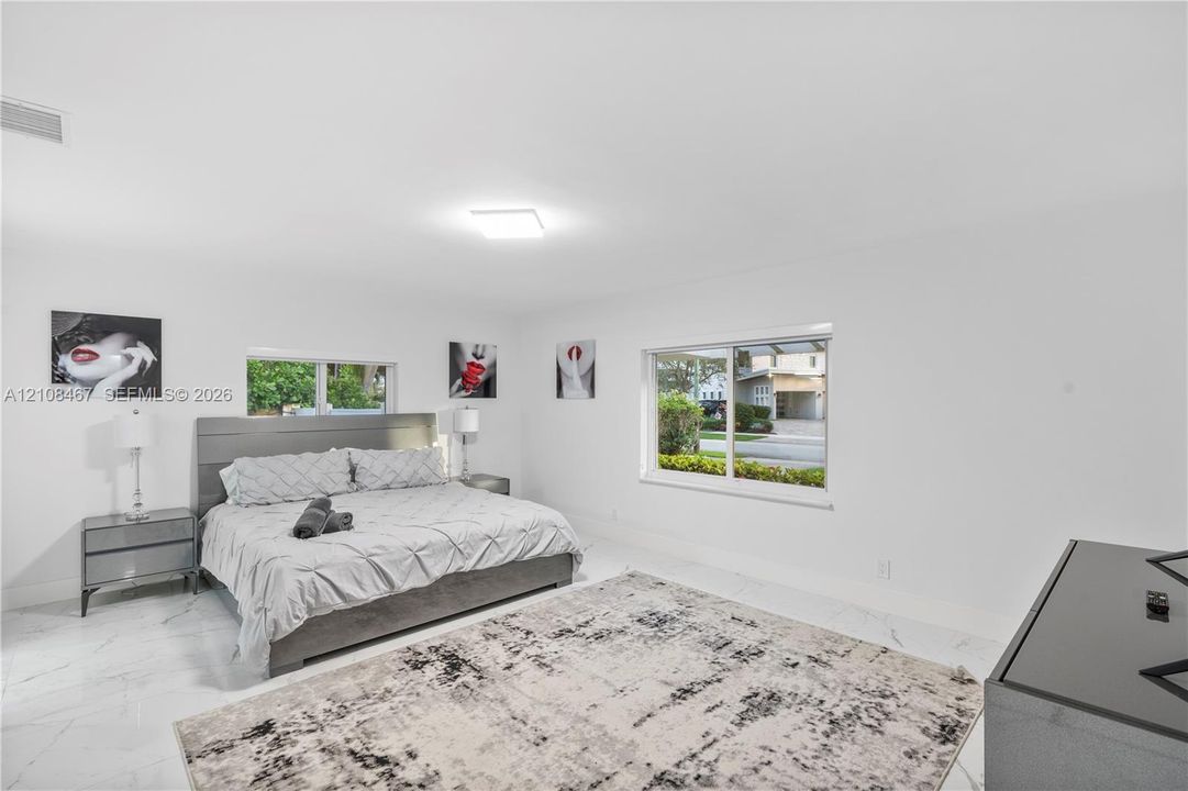 Expansive room featuring large-format white tile flooring, neutral walls, and dual sliding windows