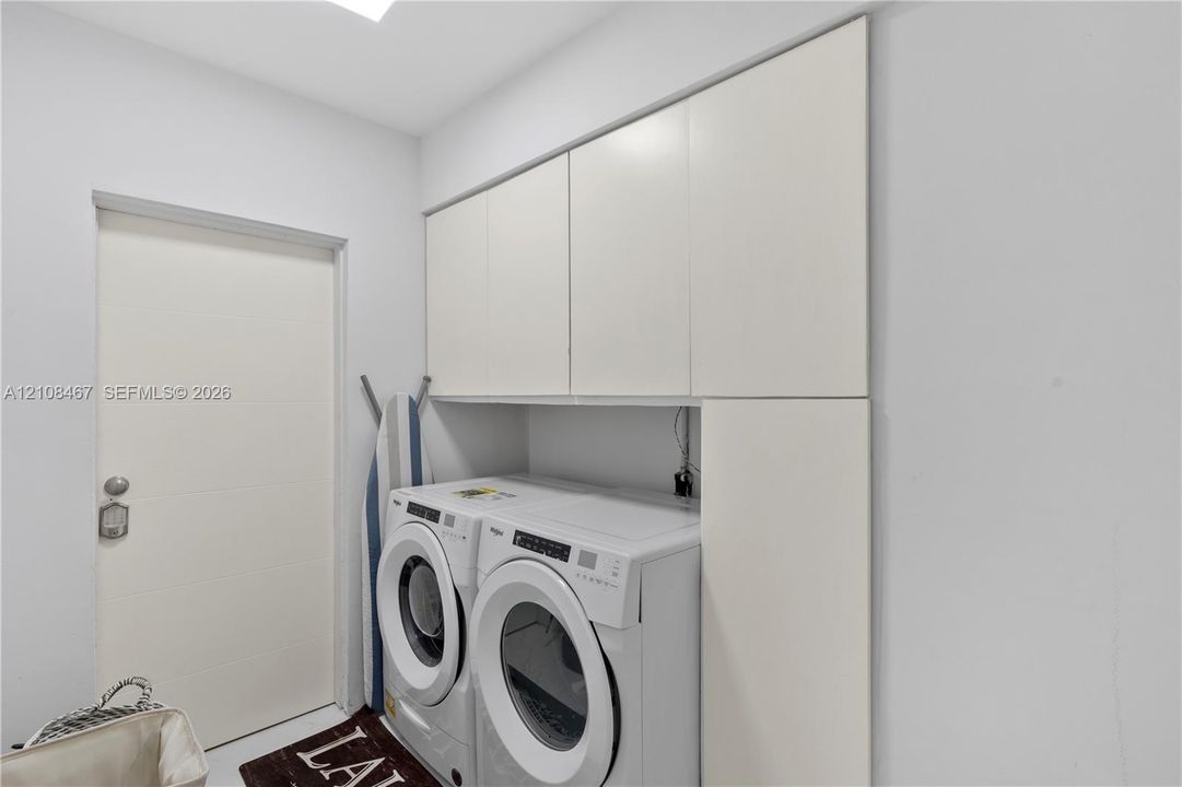 Utility room featuring white, flat-panel built-in cabinetry providing overhead and full-height vertical storage