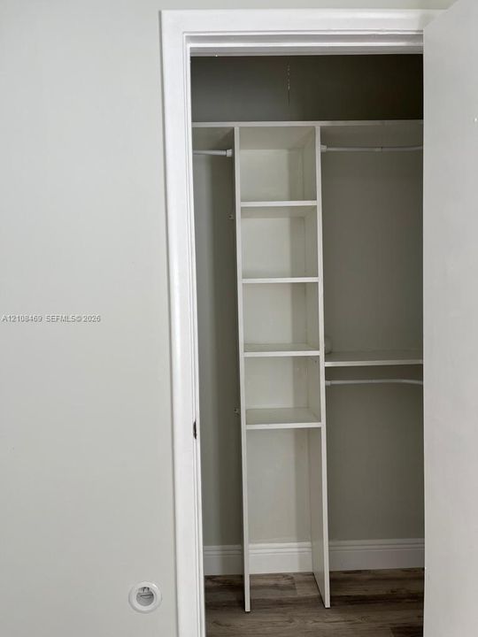 Closet featuring built-in vertical shelving and dual metal hanging rods.