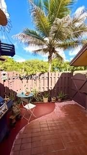 Enclosed courtyard featuring terracotta tile flooring, a privacy fence with a gated entry, and a mature palm tree