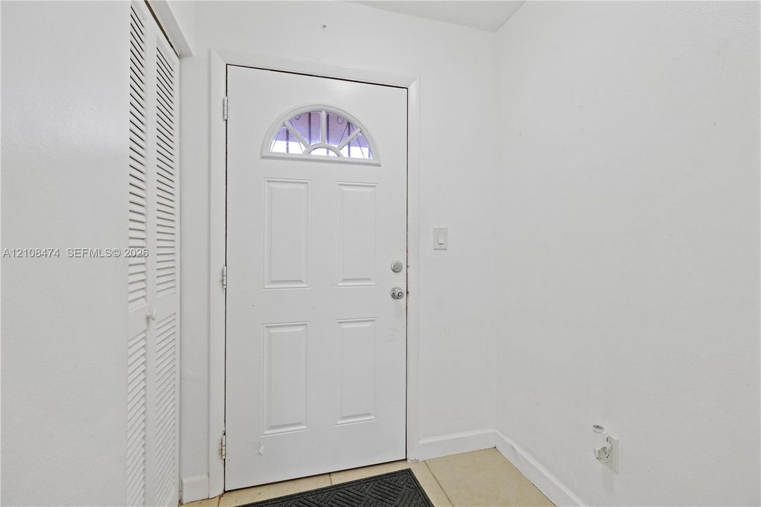 Entryway featuring a four-panel door with a semi-circular transom window and a floor-to-ceiling closet with louvered double doors