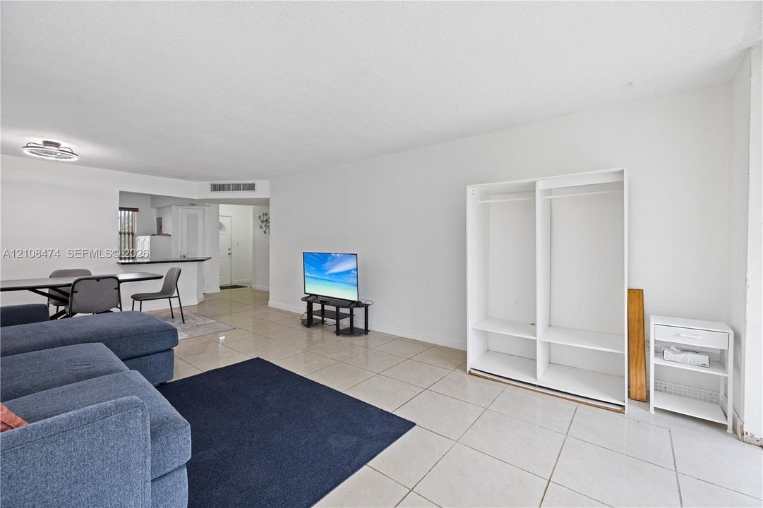 Open-concept interior featuring light-colored tile flooring, neutral wall finishes, and a built-in white floor-to-ceiling storage unit