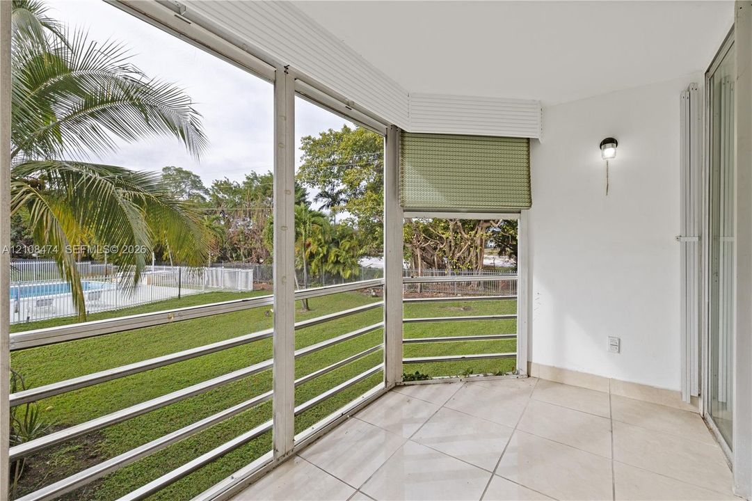 Enclosed patio featuring light-toned tile flooring, floor-to-ceiling screen panels with horizontal railings, and a mounted wall sconce