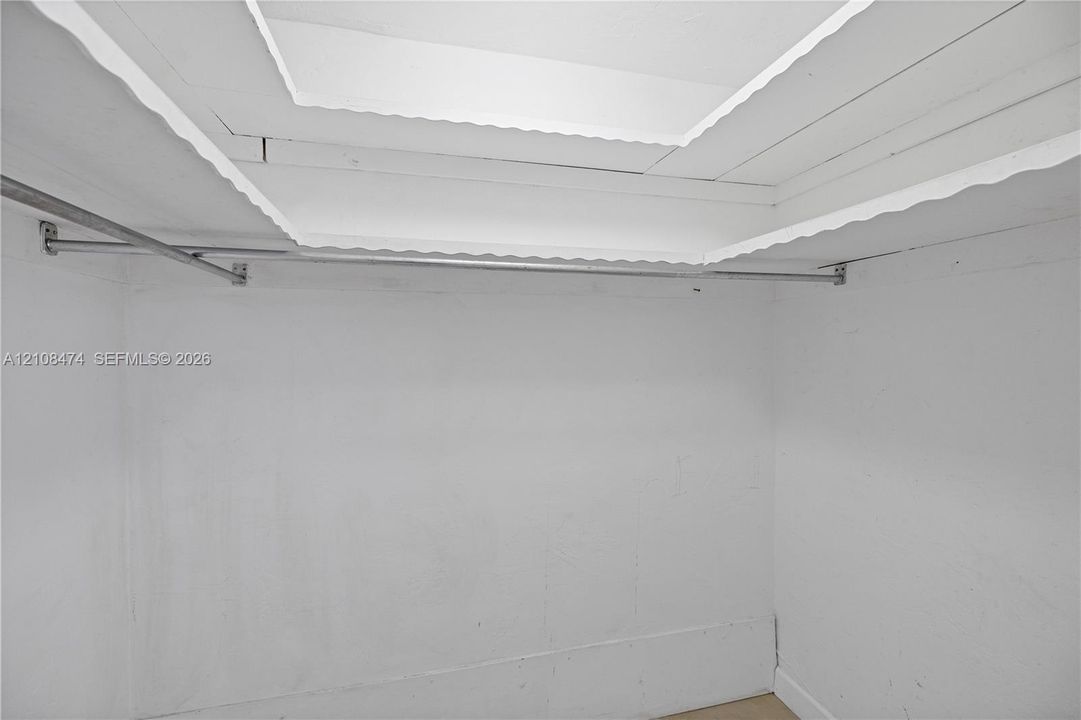 Storage area featuring a tray ceiling with recessed lighting and a wall-mounted metal garment rod