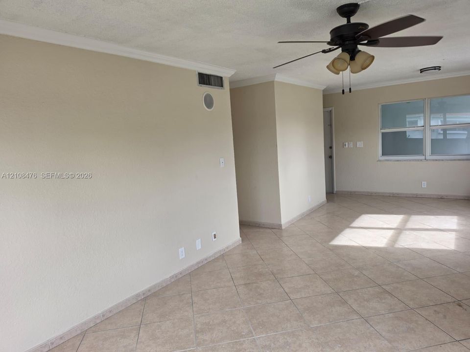 Neutral-toned interior featuring ceramic tile flooring, crown molding, and a ceiling fan with integrated lighting