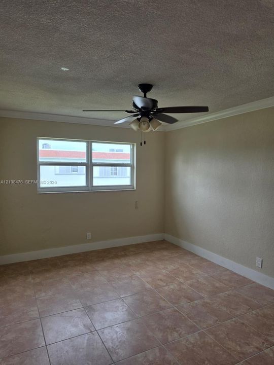 Room featuring tile flooring, crown molding, and a multi-light ceiling fan