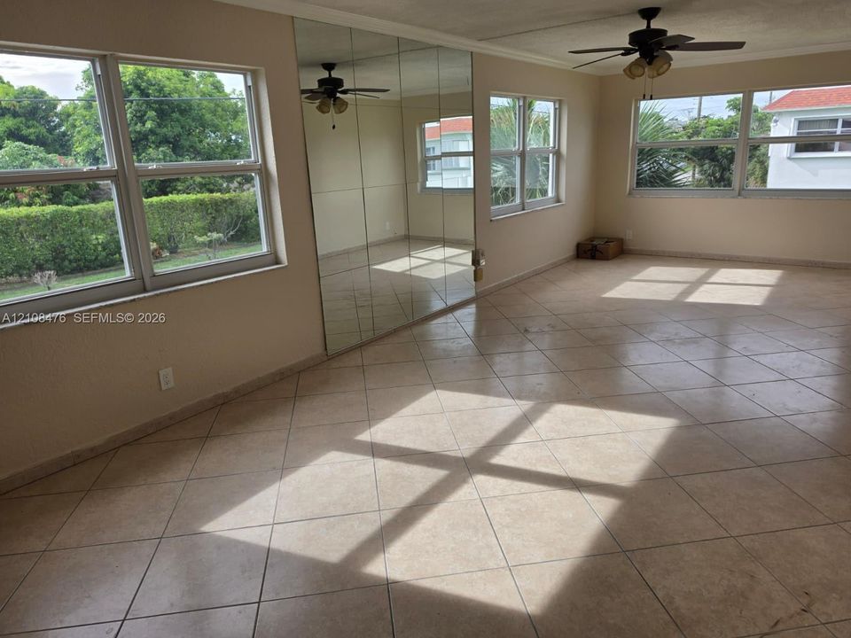 Large multi-pane window configuration, neutral ceramic tile flooring, floor-to-ceiling wall mirror, and dual ceiling-mounted fans