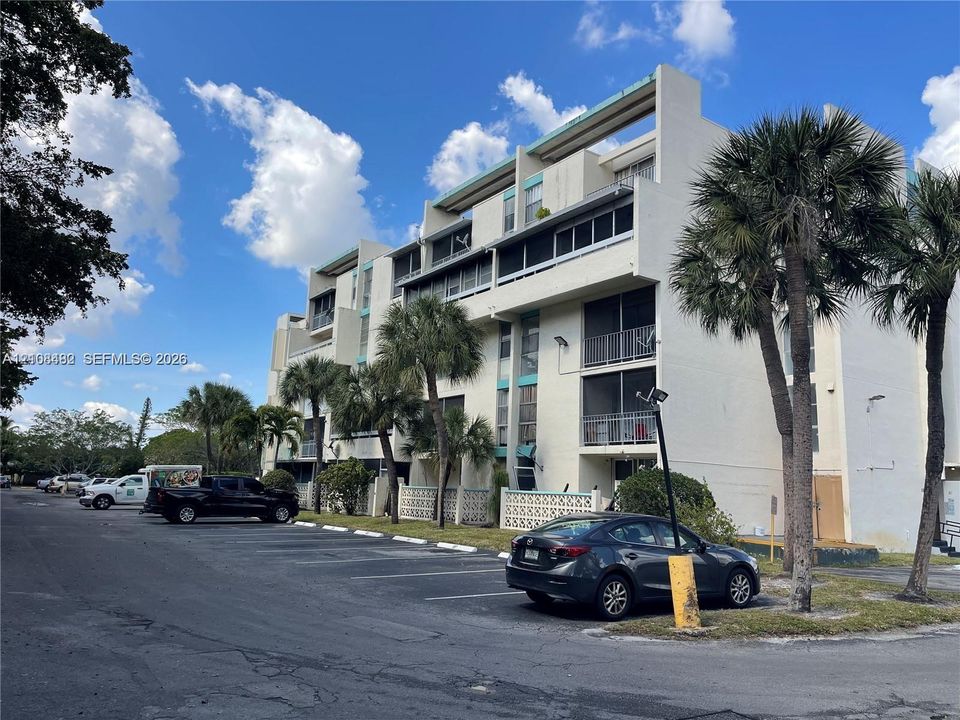 Multi-story residential building exterior featuring concrete facade, screened balconies, and decorative lattice screening