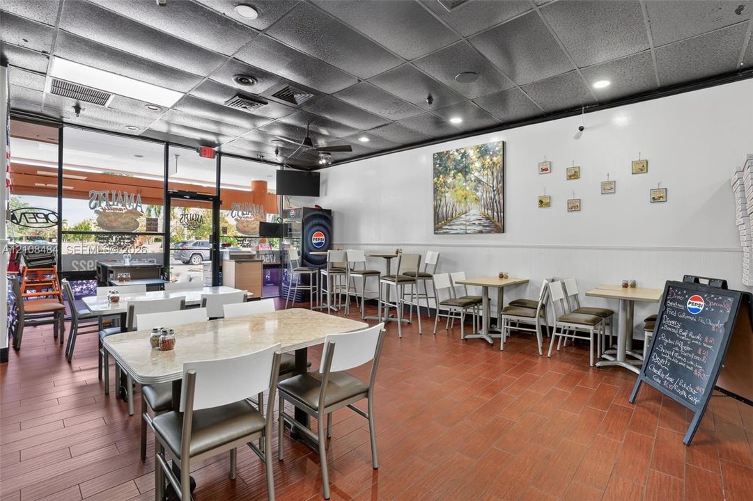 Commercial interior featuring tile flooring, a suspended acoustic tile ceiling, recessed lighting, and floor-to-ceiling storefront windows