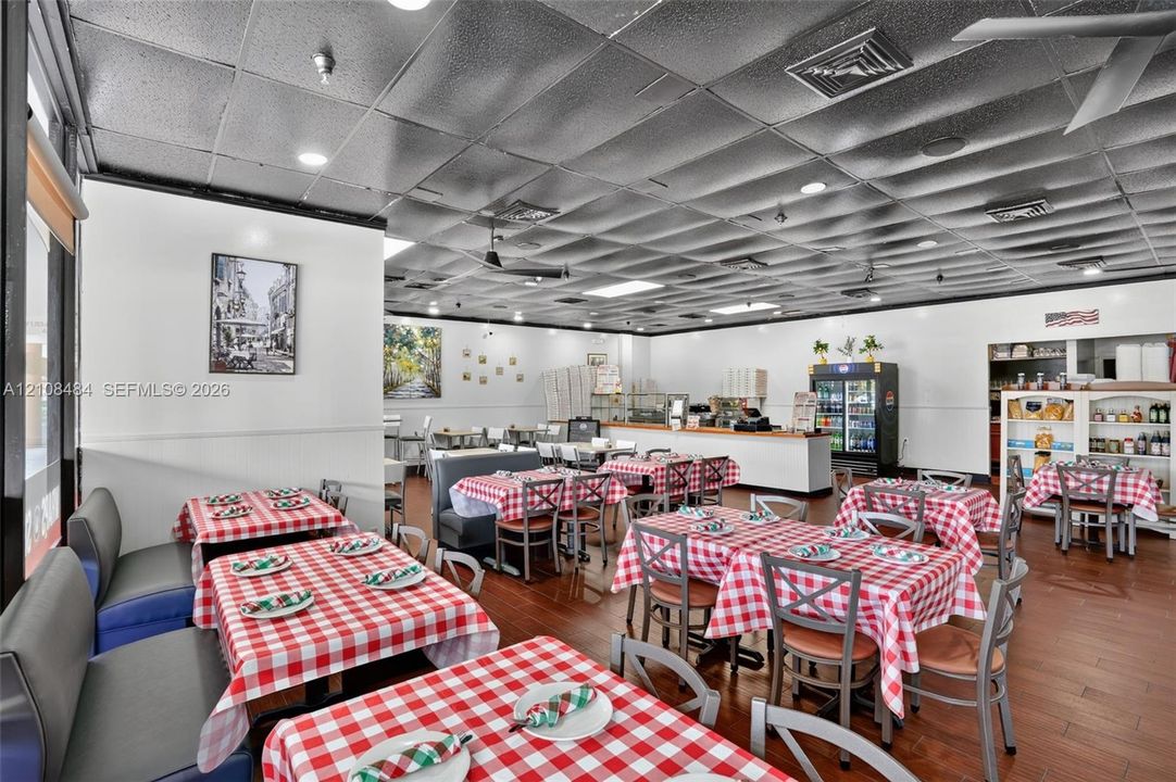 Expansive interior space featuring a metallic dropped ceiling, recessed lighting, and wood-finish flooring