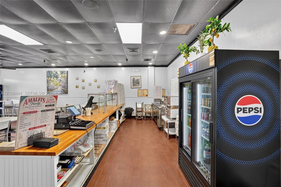 Commercial interior featuring a drop ceiling with recessed lighting, wood-finish flooring, and a long service counter with a wood-grain surface