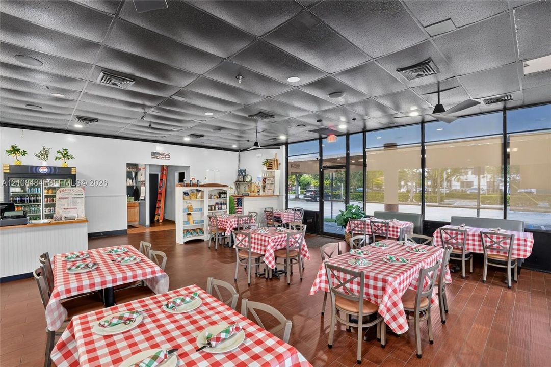 Open-concept interior space featuring tile flooring, a textured acoustic tile ceiling, and floor-to-ceiling glass panel windows