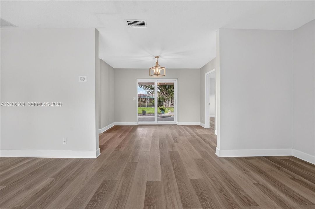 Interior space featuring wood-finish flooring, neutral wall tones, a geometric metal chandelier, and sliding glass doors