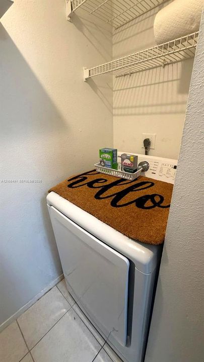 Laundry area featuring tile flooring and dual-tier wire shelving