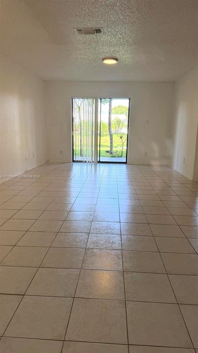 Neutral-toned tile flooring, sliding glass door, and flush-mount ceiling lighting