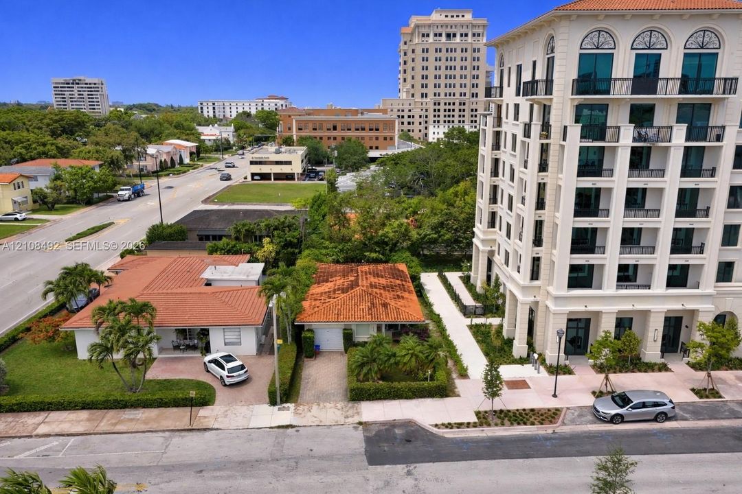 Aerial perspective of a multi-story residential building featuring arched windows, metal balconies, and a white stucco exterior