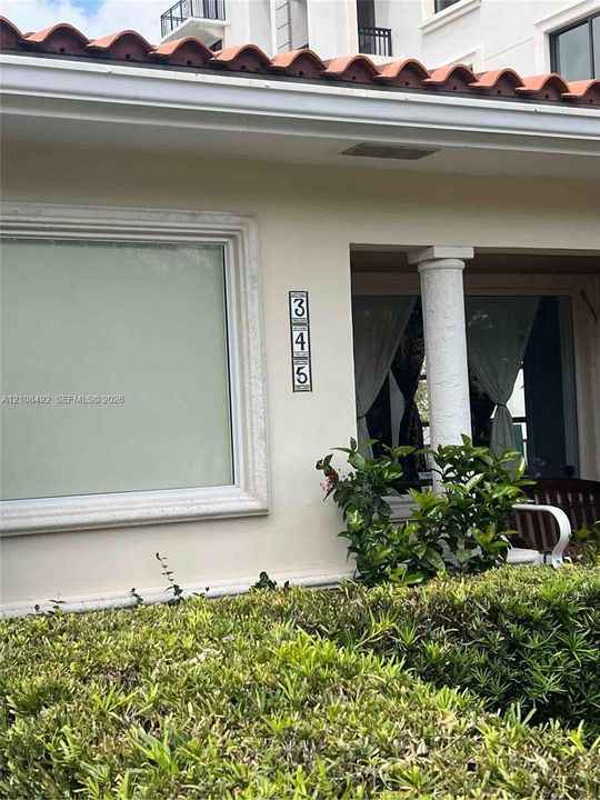 Exterior facade featuring a terracotta tile roof, decorative column, and stucco finish with detailed window molding